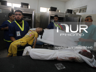 A Palestinian medic carries the body of five year old, Rana Duheir (L), as another girl from the Abu Zeid family lies on a table, after they...