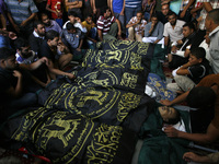A Palestinian mourners gather around the bodies of fifteen members of the Abu zeid, Duheir and al-Hashash families, that were killed in an I...