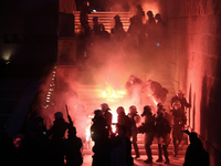 Police officers stand amid smoke from flares and molotov coctails thrown by protestos, at the monument of the Unknown Soldier, outside the G...
