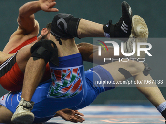 Younes Sarmastidizaji (Blue) of Iran copetes against Nodirjon Safarov of Uzbekistan in the Mens Freestyle Wrestling 65kg semi-finals during...