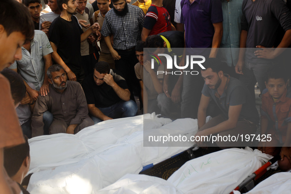 Palestinian mourn over the bodies of ten members of the al-Astal family, that were killed in an Israeli air strike on their homes, during th...