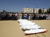 Palestinian mourners pray in front of the bodies of ten members of the al-Astal family, that were killed in an Israeli air strike on their h...