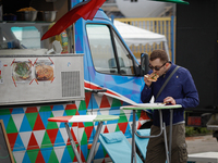 A man is seen eating a slice of pizza at a food truck rally on 20 May, 2017. Food trucks have become increasingly popular in recent years in...