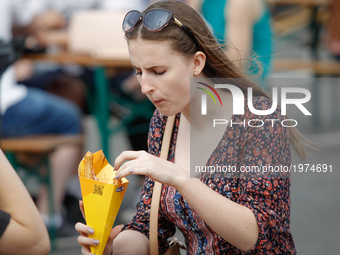 People are seen eating churros with chocolate sauce at a food truck rally in Bydgoszcz, Poland on 20 May, 2017. (