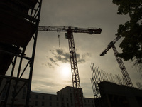 Cranes are pictured against the sun in a construction site in Berlin, Germany on May 23, 2017. (