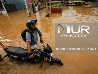 A Sri Lankan motorcyclist pushes his bike across a road inundated by floods at Kaduwela, 20kms away from capital city Colombo, Sri Lanka. Fr...