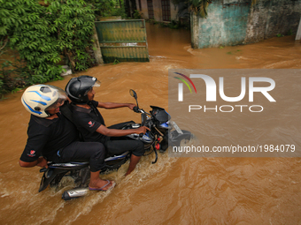 A Sri Lankan motorcyclist rides his bike across a road against the inundated water caused by floods at Kaduwela, 20kms away from capital cit...
