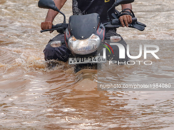 A Sri Lankan motorcyclist rides his bike across a road against the inundated water caused by floods  at Kaduwela, 20kms away from capital ci...