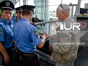 KIEV, UKRAINE - JULY 30: A passenger shows to policemen the lighter in a shape of a gun as Boryspil International Airport security services...