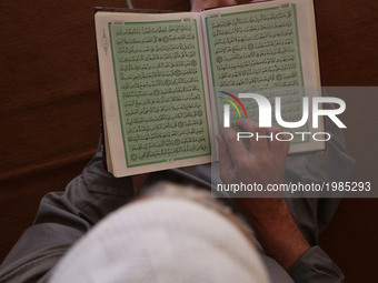 A Palestinian man reads a copy of the Koran, Islam's holiest book, on the first day of fasting in the Muslim holy month of Ramadan, at the a...