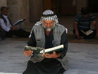 Palestinian men read copies of the Koran, Islam's holiest book, on the first day of fasting in the Muslim holy month of Ramadan, at the al-O...