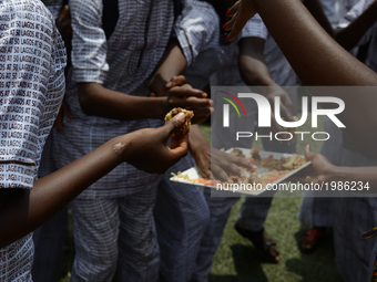 Pupils in native attire have fun, pick piece of cake, after their cultural performance during the Children’s Day parade at Agege Stadium in...