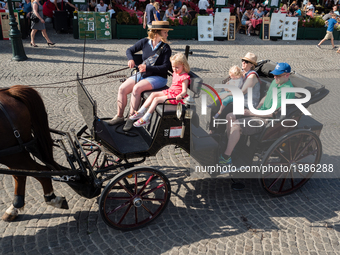 Local coach drives a horse carriage tourists through a historic street of Bruges, Belgium on May 24, 2017.  During one of the warmest days o...