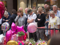 People queue and walk past the floral tributes, for the victims of the Manchester Arena bombing, in St. Anne's Square in Manchester, United...