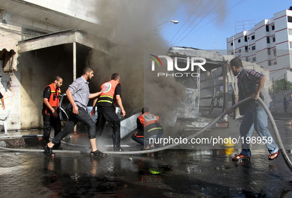 Palestinian firefighters try to put out the fire in a van after an Israeli air strike, in Gaza City, on 31 July 2014. 