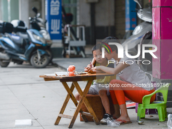 A child studies with his mother on the street outside their family business and home in Huangshi center.
On Monday, September 19, 2016 in Hu...
