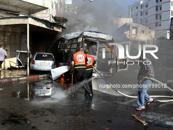 Palestinian firefighters try to put out the fire in a van after an Israeli air strike, in Gaza City, on 31 July 2014. (
