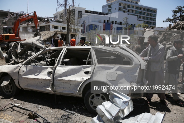 An Afghan man inspects a damaged car at the site of a car bomb explosion in Kabul, capital of Afghanistan, May 31, 2017. At least 64 people...