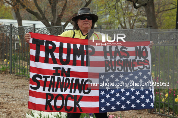 Aboriginal man holds an upside-down American flag with the words 'Trump has no business in Standing Rock' as hundreds of Canadians took part...