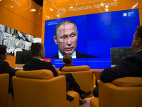 People watches a live broadcast of Russian President Vladimir Putin's address to the plenary session as part of the 2017 St Petersburg Inter...