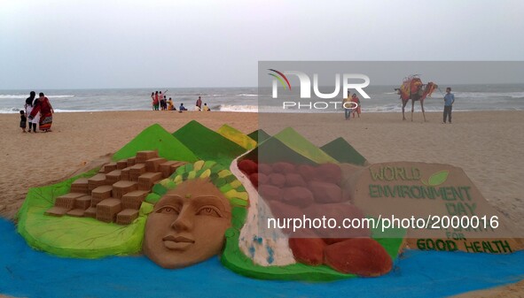 Visitors look near to sand sculpture creating by local sand artists on the eve of World Environment Day at the Bay of Bengal Sea's eastern c...