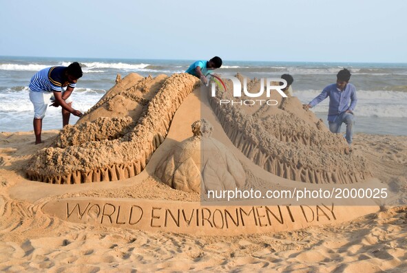 Visitors look near to sand sculpture creating by local sand artists on the eve of World Environment Day at the Bay of Bengal Sea's eastern c...