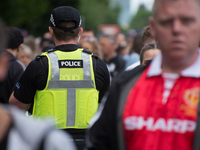 Police officers patrol as people arrive for the One Love Manchester benefit concert at the Old Trafford cricket ground in Trafford, United K...