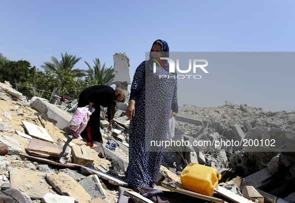 Palestinian women inspect a destroyed of their house in the Bureij refugee camp in the central Gaza Strip on 01 August 2014. 