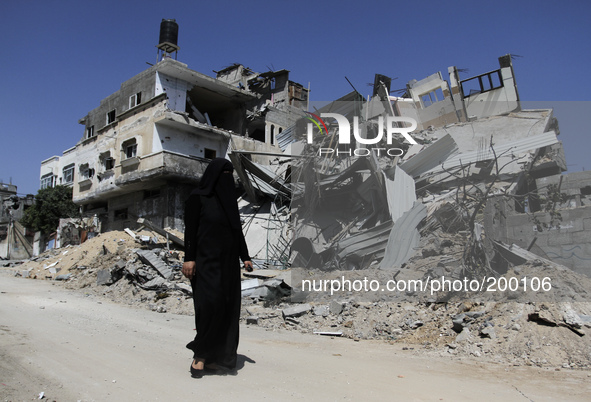 A Palestinian woman walks in front of a destroyed house in the Bureij refugee camp in the central Gaza Strip on 01 August 2014. 