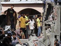 Palestinians search for bodies at the rubble of the destroyed house for the Al-Bayoumi family in the al-Nusairat refugee camp in the central...