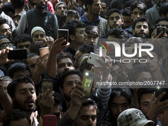Kashmiri villagers click pictures with their mobile phones during the funeral of a teenager Adil Magray at Shopian, about 60 kilometers (38...