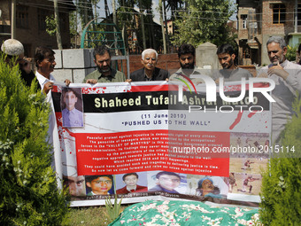 Family members and the pro-independence group leaders hold a banner as they shout pro-freedom slogans  in front of the Grave of Tufail Matoo...