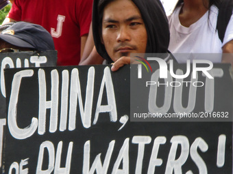 A protester holds a placard during a rally coinciding the 119th Philippine Independence Day outside the Chinese consulate in the financial d...