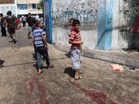  	Palestinian walk past trails of blood following an Israeli military strike on a UN school in Rafah, in the southern Gaza Strip on August 3...