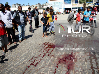  	Palestinian walk past trails of blood following an Israeli military strike on a UN school in Rafah, in the southern Gaza Strip on August 3...