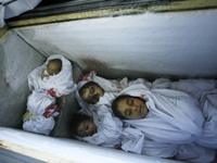 picture taken on August 3, 2014, at the morgue in Rafah in the southern Gaza Strip shows the bodies of a baby and two children lying in an i...