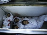 picture taken on August 3, 2014, at the morgue in Rafah in the southern Gaza Strip shows the bodies of a baby and two children lying in an i...