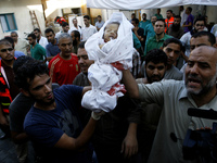 Relatives carry the body of a baby during the funeral of at least 9 members of the same al-Ghul family who died after their house was hit by...