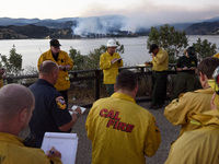 Firefighters during an evening briefing as the Castaic Lake fire burns in the background. Castaic, California on June 17, 2017. Firefighters...