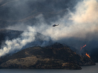 A Los Angeles County Fire Department helicopter flies over Castaic Lake during a wildfire in Castaic, California on June 17, 2017. Castaic,...