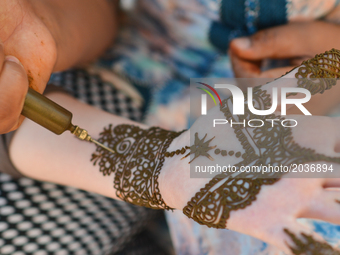 A Maroccan girl has decorative henna designs applied to her hands at a roadside stall ahead of Laylat al-Qadr celebrations in Rabat, Morocco...