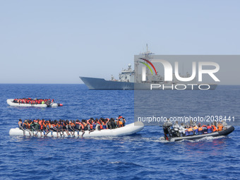 LAMPEDUSA, ITALY - MAY 19: Refugees and migrants are seen floating in an overcrowded rubber boat in front of a European war ship as they wai...