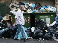 A man pases in front of garbage in central Athens on June 23, 2017. Piles of rubbish accumulate around overflowing bins in Athens, in the wa...