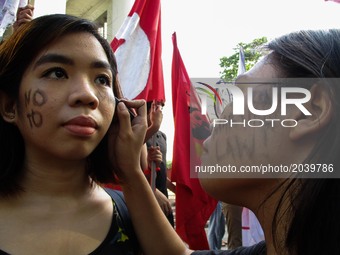 A student activist writes a slogan on another student's cheek during a rally against Martial Law in Mindanao at the University of the Philip...