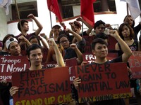 Student activists holding slogans raise clenched fists during a rally against Martial Law in Mindanao at the University of the Philippines i...