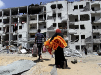 Palestinians salvage some of belongings from the rubble of their destroyed apartment in a building hit by an Israeli strike in Beit Lahiya,...