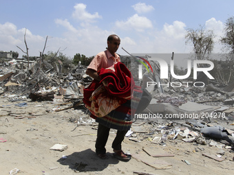 A Palestinian man carries some of his belongings after salvaging them from his destroyed apartment in a building hit by an Israeli strike in...