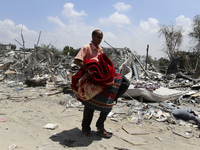 A Palestinian man carries some of his belongings after salvaging them from his destroyed apartment in a building hit by an Israeli strike in...