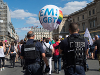 Activists walk beside a security official while taking part in the Gay Pride parade in Paris on June 24, 2017. 2017 marks the 40th anniversa...