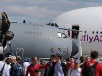 Visitors walk on the tarmac in front of  a French Air Force Airbus A400M transport plane and an Airbus A380 on the last day of the Internati...